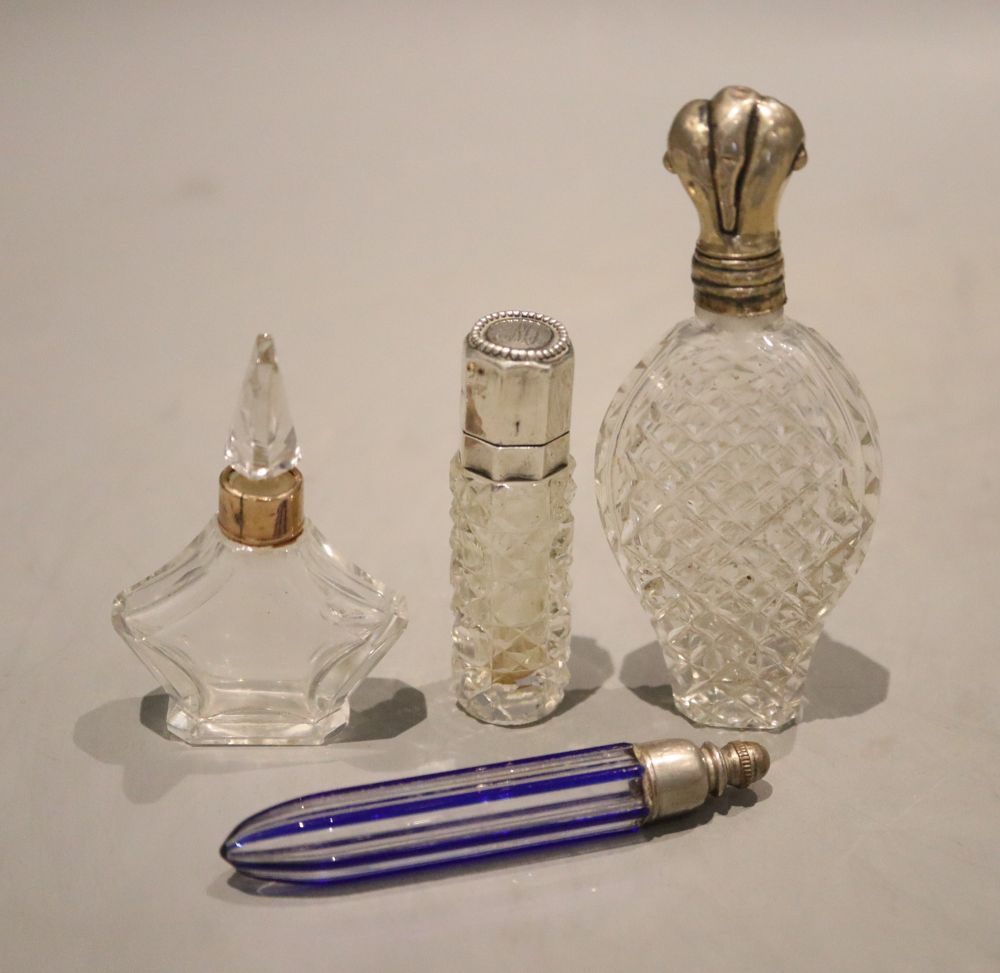 Four assorted early 20th century scent bottles including two white metal mounted and one 9ct gold mounted, largest 9.9cm.
